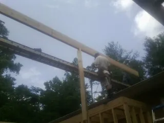 Carpenter setting a ridge beam over a new addition frame — Ice Dam Removal by Roofing Brothers in Ulen
