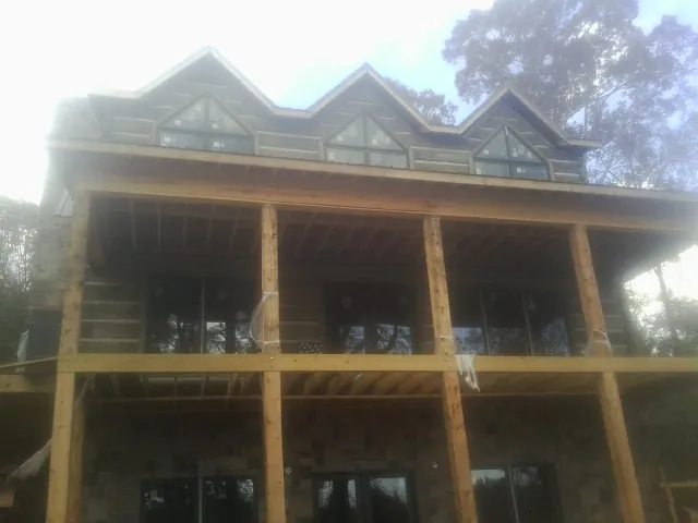 Dormers and porch framing on a large log home under construction — Roof Coating work by our crew in Ulen