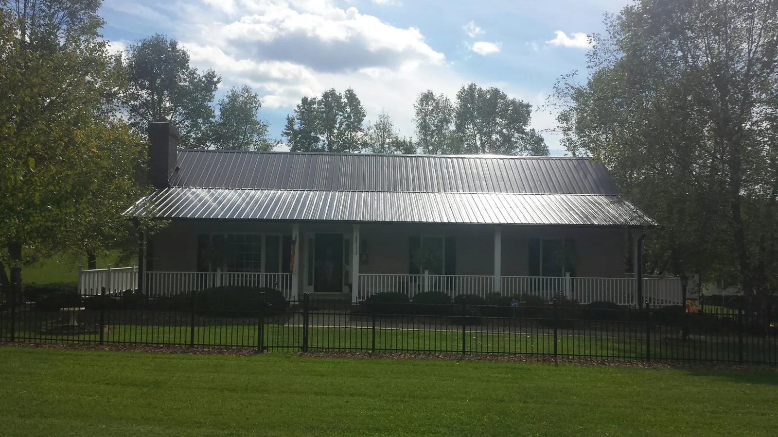 Gray metal roof on a brick ranch with a full width front porch — Gutter Guard Installation work by our crew in Ulen