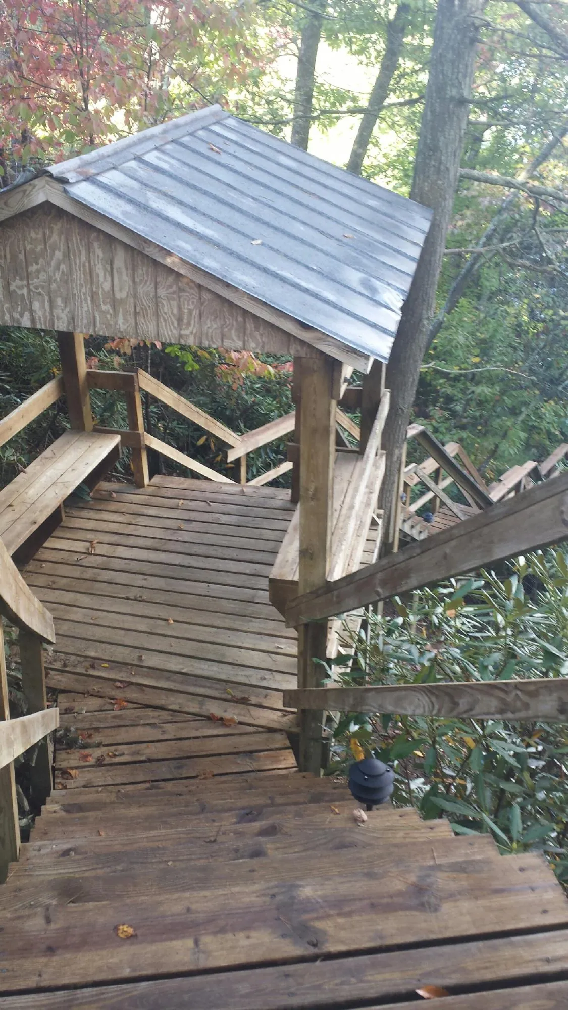Metal roofed shelter over wooden steps on a wooded walkway — Skylight Repair & Installation work by our crew in Ulen