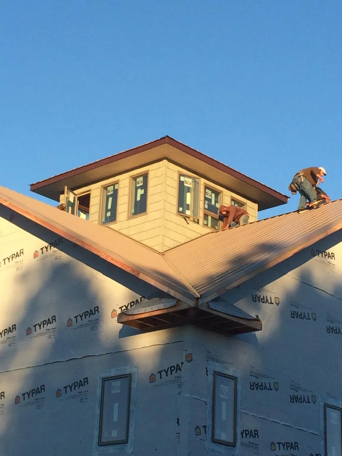 Roofers working around a rooftop cupola on a new metal roof at sunset — Roof Waterproofing in Ulen by Roofing Brothers